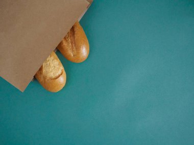 Two delicious french baguettes in a craft bag on a green background with space for text, recipe, advertising