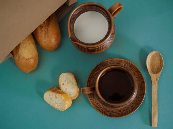 Té y leche en cerámica antigua, baguette francesa en una bolsa de artesanía, cuchara de madera sobre un fondo verde, vista superior. Puesta plana — Foto de Stock