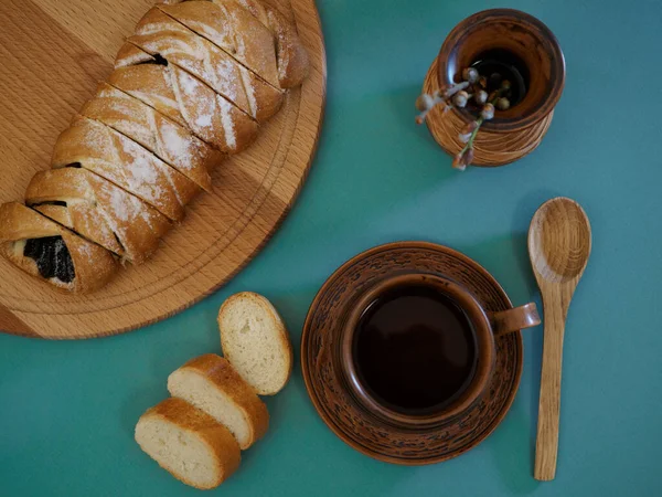 Beautifully served breakfast in earthenware with delicious fresh pastries on a wooden board, a wooden spoon and pussy willow in a clay vase on a green background — стоковое фото