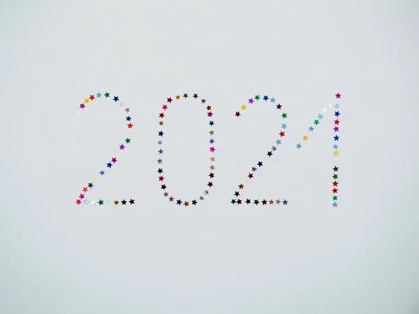 Mutlu yıllar 2021. İzole edilmiş 2021 yazıtları beyaz arkaplan görünümlü çok renkli parlayan yıldız konfetisinden