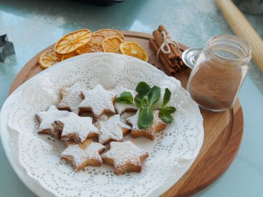 Tahta tepside pudra şekerli zencefilli kurabiyeler. Tarçın, ahşap bir tahtanın üzerinde kurutulmuş portakal