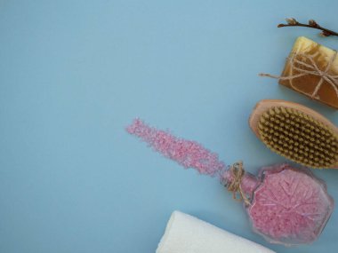 Mavi arka planda, fotokopi alanı ve üst görünümü olan ev spa vücut bakımı araçları. Kuru fırça masajı, deniz tuzu vücut fırçası.