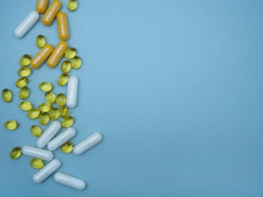 D vitamini, B vitamini, C vitamini mavi zemin üzerinde fotokopi alanı, üst manzara, düz yatak. Sağlığı iyileştirmek için kapsüllerdeki vitaminler. Sağlığınıza dikkat edin.