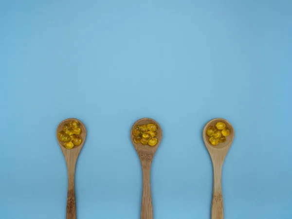 Vitamina D en cucharas de madera sobre fondo azul con espacio para texto, vista superior, plano — Foto de Stock