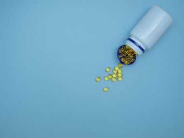 Sarı yumuşak kapsüllerde balık yağı, D vitamini, E vitamini mavi arka planda dağınık plastik bir kavanozda. Boşluğu kopyala, düz yat, üst görünüm