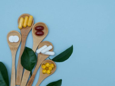 D vitamini, B, E, Omega 3, çinko ahşap kaşıklarda yeşil yapraklarla süslenmiş fotokopi alanı, üst görünüm