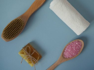 Mavi arka planda spa tedavileri için malzemeler, düz döşeme, üst manzara. Deniz tuzu banyosu, kuru masaj fırçası vücut güzelliğini korumak için.
