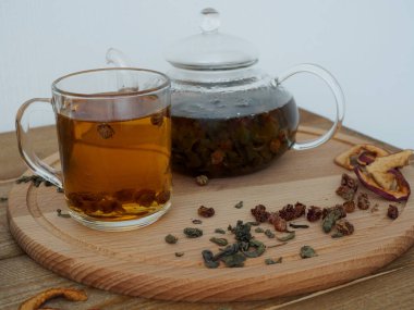 Tahta tepside çaydanlıkta sıcak siyah bitki çayı, beyaz arka planda çay. Kurutulmuş meyve ve meyve.