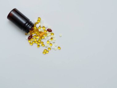 Çeşitli vitaminler D, E, C balık yağı koyu plastik bir kavanozda beyaz bir zemin üzerine serpiştirilmiş fotokopi alanı, üst görünüm, düz yatış