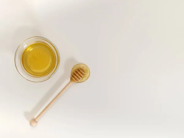 Composition of honey in a bowl and honey dipper on a white background with copy space. Top view, flat lay — Stock Photo, Image
