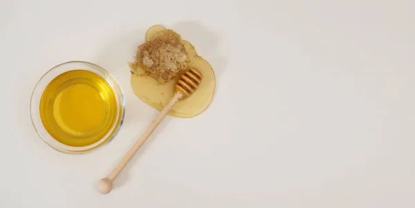 Natürlicher Honig in einer Schüssel, Honig-Holzlöffel und Wabe auf weißem Hintergrund. Banner, flache Lage, Draufsicht — Stockfoto
