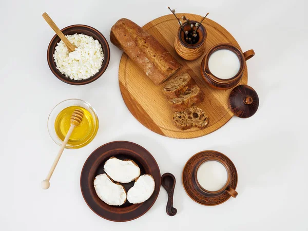 Desayuno saludable con productos lácteos en vajilla y miel de flores frescas sobre fondo blanco, plano, vista superior — Foto de Stock