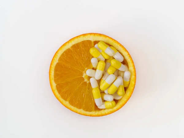 Vitamine C capsules in een halve sinaasappel op een witte achtergrond, bovenaanzicht, platte lay — Stockfoto