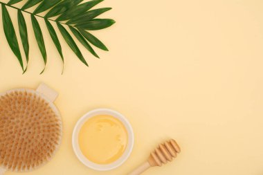 Vücut balı masajı, sarı arka planda spa tedavileri için malzemeler. Kuru fırça masajı.