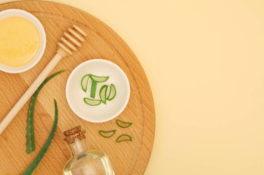 Maske, ovalama, masaj için doğal kozmetik malzemeler sarı arka planda tahta tahtada metin, üst manzara ve düz yatak için yer var. Kişisel bakım ve rahatlama için evde spa tedavileri