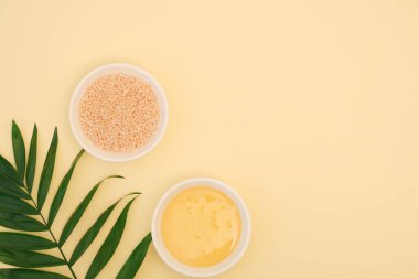 Anti-selülit vücut masajı için bir takım kozmetik malzemeler. Beyaz kâselerdeki deniz banyosu tuzu ve organik bal sarı arka planda yazı için yer var. Düz yatış, üst görünüm