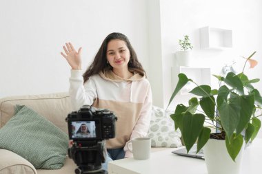 Teknoloji ve blog konsepti. Afrikalı bir kadın evdeki güzellik blogu için video kaydediyor. Önizleme ekranı ile seçici bir şekilde kameraya odaklanıyor. Güzel bir genç kadın blogcu, vlogger ya da etkili biri.