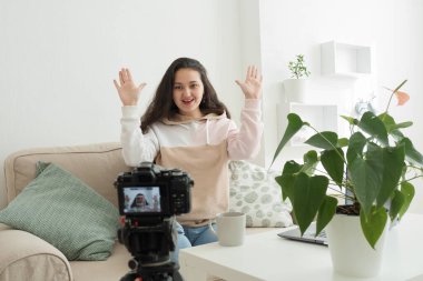 Teknoloji ve blog konsepti. Afrikalı bir kadın evdeki güzellik blogu için video kaydediyor. Önizleme ekranı ile seçici bir şekilde kameraya odaklanıyor. Güzel bir genç kadın blogcu, vlogger ya da etkili biri.