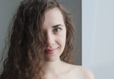 Duştan sonra ıslak kıvırcık saçlı genç bir kadının portresi. Kıvırcık umursar. güzellik ve sağlık