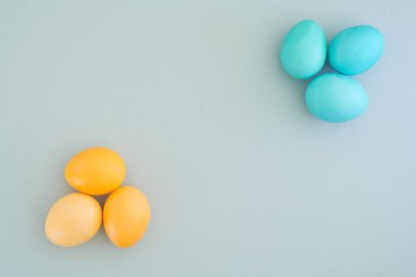 Güzel minimalist paskalya arkaplanı. Boyalı sarı ve mavi yumurtalar. Metin, üst manzara, düz yatış alanı.