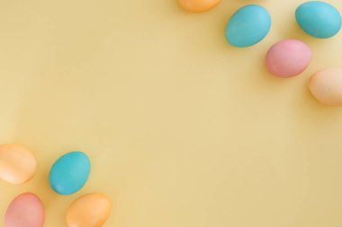 Sarı zemin üzerinde çok renkli paskalya yumurtaları metin, üst görünüm, düz yatış alanı
