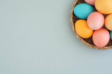 Mavi arka planda paskalya konsepti ve metin için boşluk. Paskalya yumurtası dolu bir sepet. Üst manzara, düz uzanma