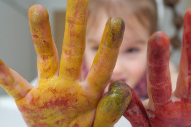 Çok renkli avuçlar, yakın plan küçük bir kızın boyası. Kız çiziyor.