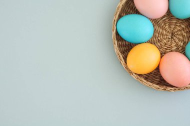 Renkli yumurtalarla birlikte minimalist paskalya arkaplanı mavi bir arka planda mavi bir sepetin içinde metin, üst görünüm ve düz yatış yeri ile.