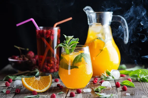 Ahşap arka plan üzerinde turuncu ve ahududu içecekler