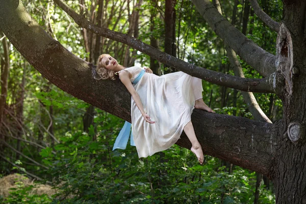 Jovem menina bonita deitada em uma grande árvore no parque de verão — Fotografia de Stock