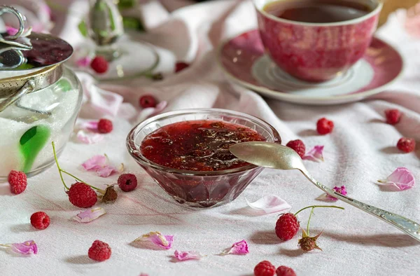 Confiture de framboises et tasse de thé sur une table dressée — Photo