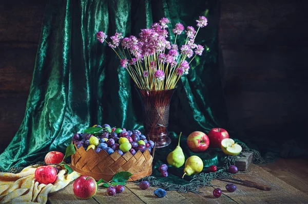 Nature morte avec prunes dans un panier et fruits dans un style rustique — Photo