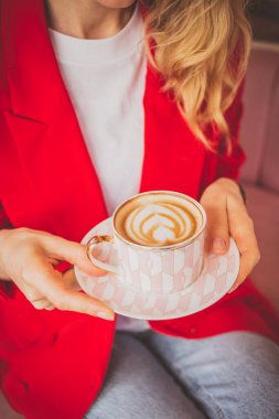 Kadın elleri sıcak kahve fincanı tutuyor.
