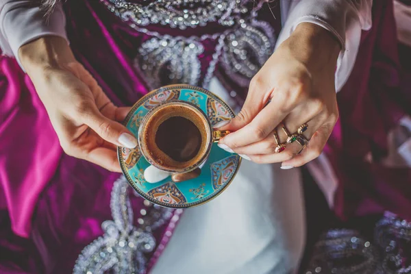 Молодая девушка в красивом восточном платье держит чашку традиционного турецкого кофе — стоковое фото