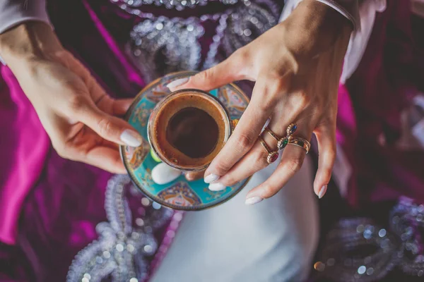 Молодая девушка в красивом восточном платье держит чашку традиционного турецкого кофе — стоковое фото