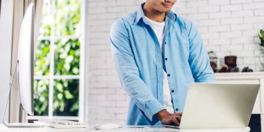 Masaüstü bilgisayarını kullanarak rahatlayan genç yaratıcı adam ev konseptinden online sohbet ve video konferansı yapıyor.