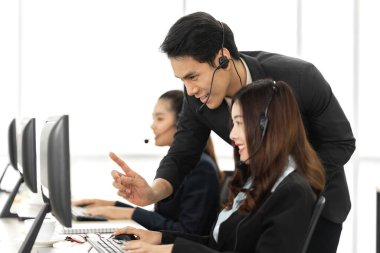 Mutlu Asyalı gülümseyen çağrı merkezi müşteri destek ekibi telefon hizmetleri çağrı merkezindeki masaüstü bilgisayarında çalışan ve kulaklıkla konuşan bir grup.