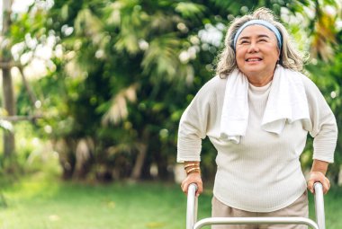 Yaşlı mutlu Asyalı kadının portresi gülümseyen ve parktaki kameraya bakan temiz hava alan. Emeklilik konsepti.