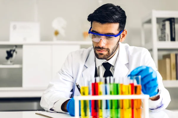 Professional scientist man research and working doing a chemical experiment while making analyzing and mixing  liquid in test tube.Young science man looking sample chemical on glass at laboratory