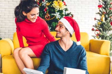 Noel Baba şapkalı romantik çift Noel ağacını süslerken ve yeni yılı kutlarken gülümserken ve birlikte vakit geçirirken eğleniyorlar. Adam, Noel zamanı evde kadınlara hediye kutusu sürprizi veriyor.