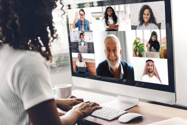 Afrika kökenli siyahi kadın konuşması, masaüstü bilgisayarlı çalışma ve evdeki iş arkadaşlarıyla çevrimiçi video konferansı kullanarak konuşuyor. Yaratıcı Afrikalı kadın iş ekibiyle görüntülü sohbet görüşmesi hakkında konuştu. Ev kavramından çalışma