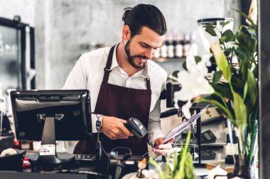 Yakışıklı sakallı baristanın portresi. Küçük işletme sahibi. Kafenin arkasında bilgisayarla çalışıyor.