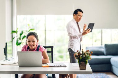 Okul çocuğu küçük kız öğreniyor ve dizüstü bilgisayara bakıyor ev ödevi yapıyor çevrimiçi eğitim sistemi ile bilgi öğreniyor. Evde öğretmenle çocuk video konferansı