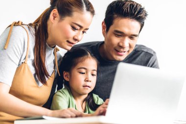 Küçük Asyalı kız öğrenen mutlu Asyalı aile babası ve annesi ile mutlu bir gülümseme içinde olun ve evde öğretmenle birlikte online eğitim e-öğrenim sistemiyle çalışan dizüstü bilgisayara bakın.