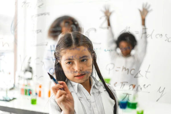 Cute little girl student child learning research and doing a chemical experiment and write scientific formulas and calculations in physics at science class.Education and science concept