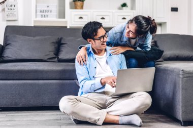 Genç Asyalı çift dizüstü bilgisayarlarını kullanarak rahatlıyor. İnternetteki video konferansında sohbet ediyorlar. Evde yaratıcı iş çifti planlama ve beyin fırtınası yapıyorlar.