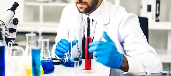 Professional scientist man research and working doing a chemical experiment while making analyzing and mixing  liquid in test tube.Young science man looking sample chemical on glass at laboratory