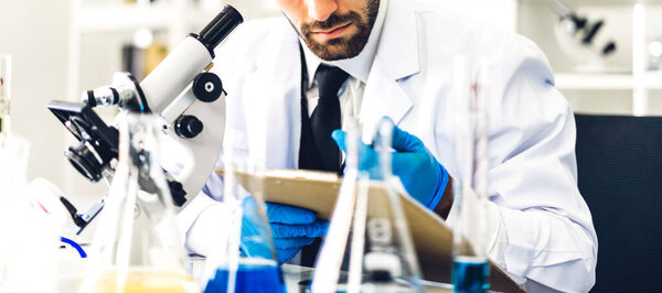 Professional scientist man research and working doing a chemical experiment while making analyzing and mixing  liquid in test tube.Young science man looking sample chemical on glass at laboratory