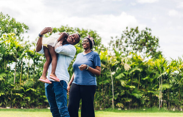 Portrait of enjoy happy love black family african american father and mother with little african girl child smiling and having fun moments good time in summer park at home