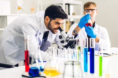 Profesyonel iki bilim adamı test tüpünde sıvı analiz ederken ve karıştırırken kimyasal bir deney yapıyor. Genç bilim adamı laboratuvarda cam üzerine kimyasal örnekler bırakıyor.